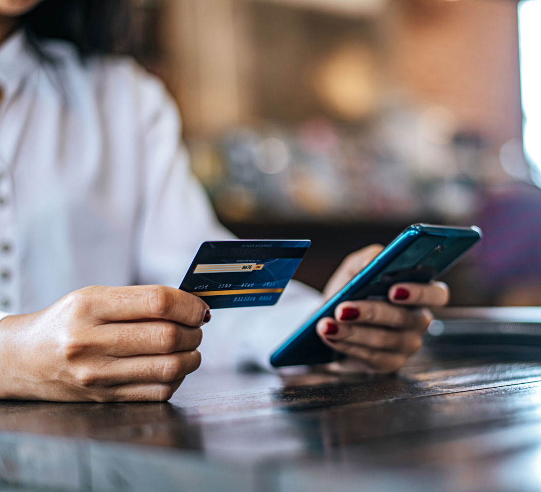 Pay for goods by credit card through a smartphone in a coffee shop.